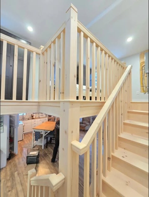 Site-built pine staircase and open railing overlooking a kitchen and living room