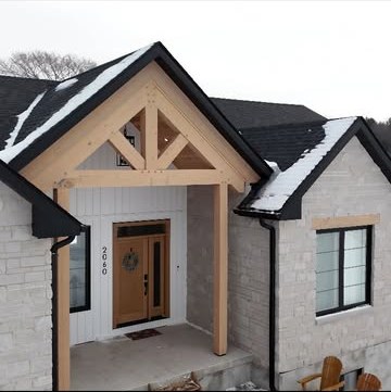 Timber entry porch with an exposed king-post truss over a wood front door, flanked by white brick