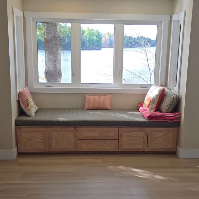 Built-in window bench with oak drawer fronts and a cushioned seat, looking out over the water